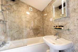 A bathroom with a bathtub, a sink, a shower, and a marble wall.