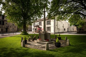 A courtyard with a central monument, surrounded by potted plants and a chain-link fence.