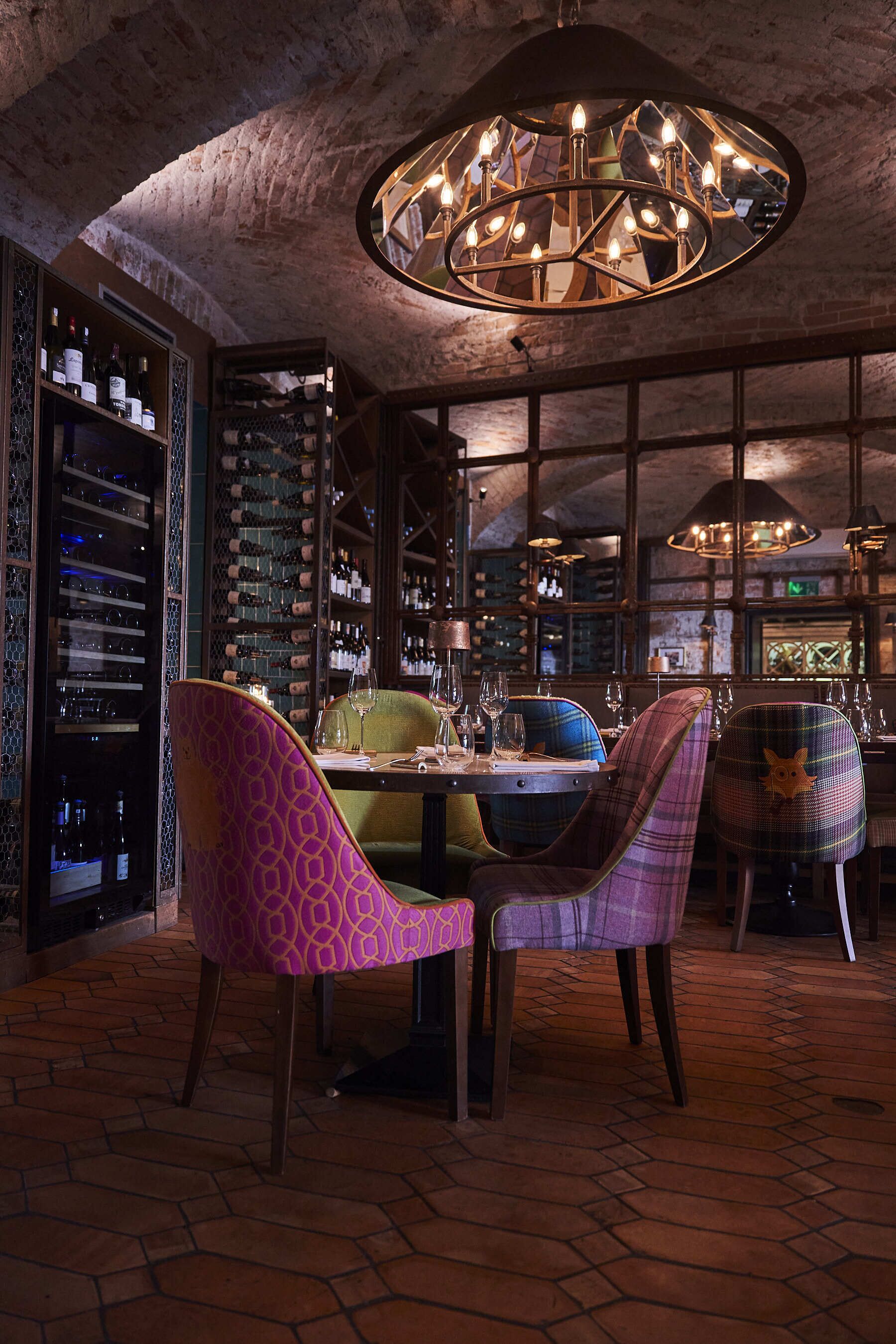 Un restaurante con techo de ladrillo, candelabro y una bodega de vinos.