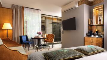 A hotel room with a bed, a desk, a chair, a TV, and a minibar.