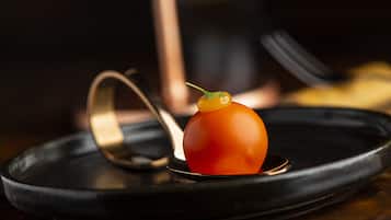 A dish with a tomato centerpiece on a black plate.