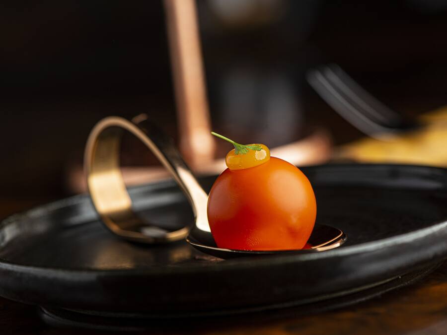 A dish with a tomato centerpiece on a black plate.