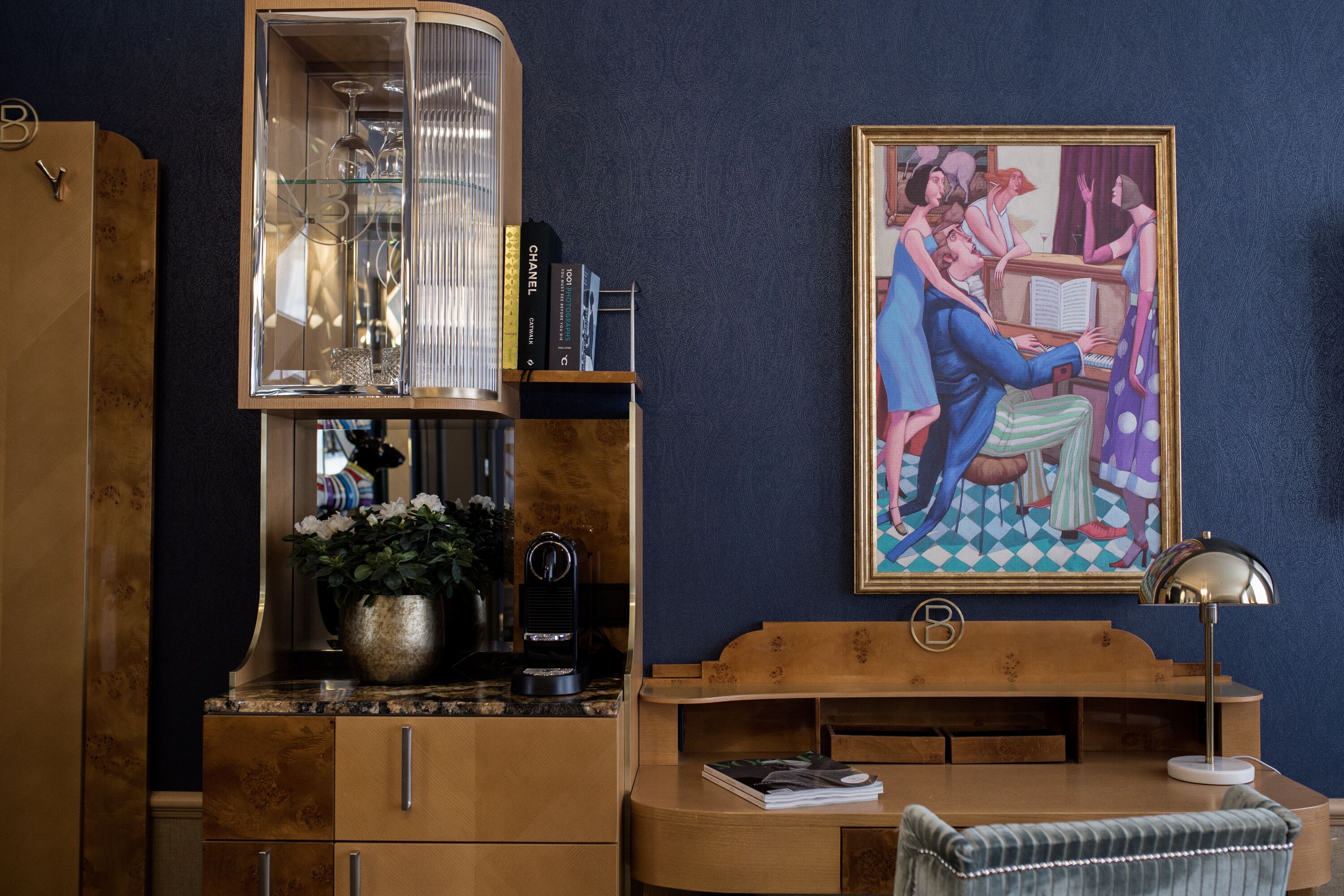 Una habitación con un armario de madera, una vitrina de vidrio, un cuadro y un escritorio con una lámpara.