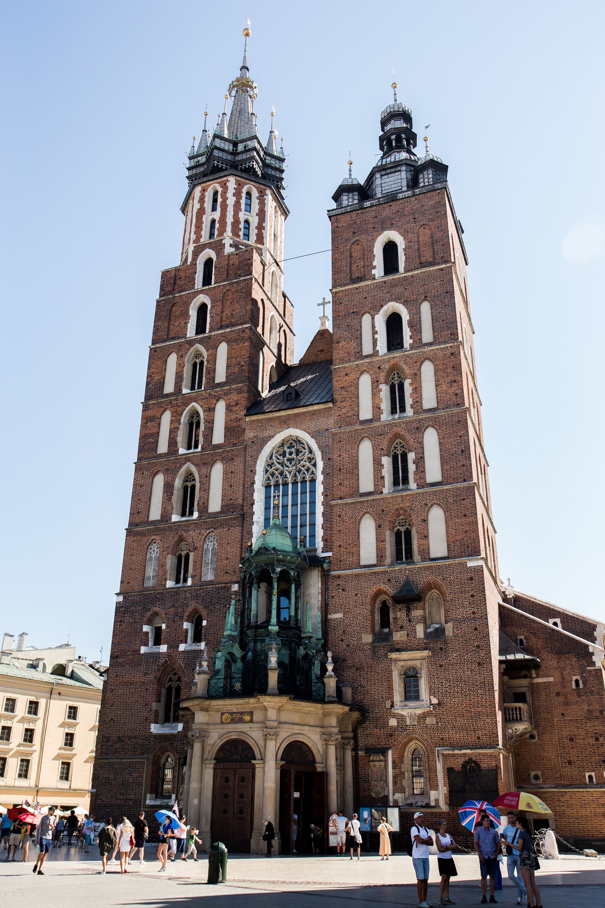 Ein großes Backsteingebäude mit einem markanten Turm und einem Eingang mit Gründach.