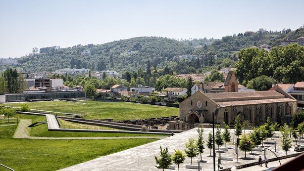 A historic building with a large open courtyard, surrounded by trees and modern buildings in the background. - JR Studios & Suites (Coimbra)
