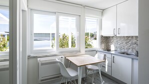 A modern kitchen with white cabinets, a wooden table, and two white chairs. - JR Studios & Suites (Coimbra)