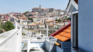 A balcony with a view of a densely packed cityscape, including buildings with red-tiled roofs and a prominent church tower. - JR Studios & Suites (Coimbra)