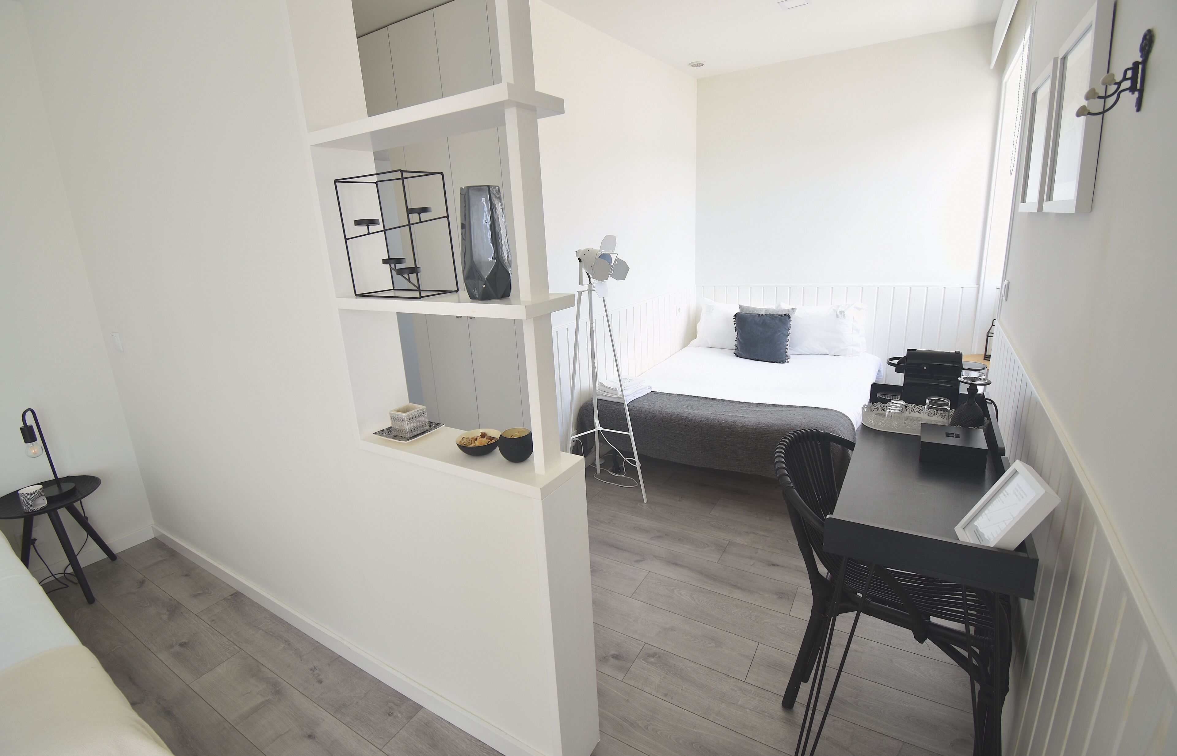 Een slaapkamer met een bed, nachtkastje, lamp en een klein bureau met een stoel.