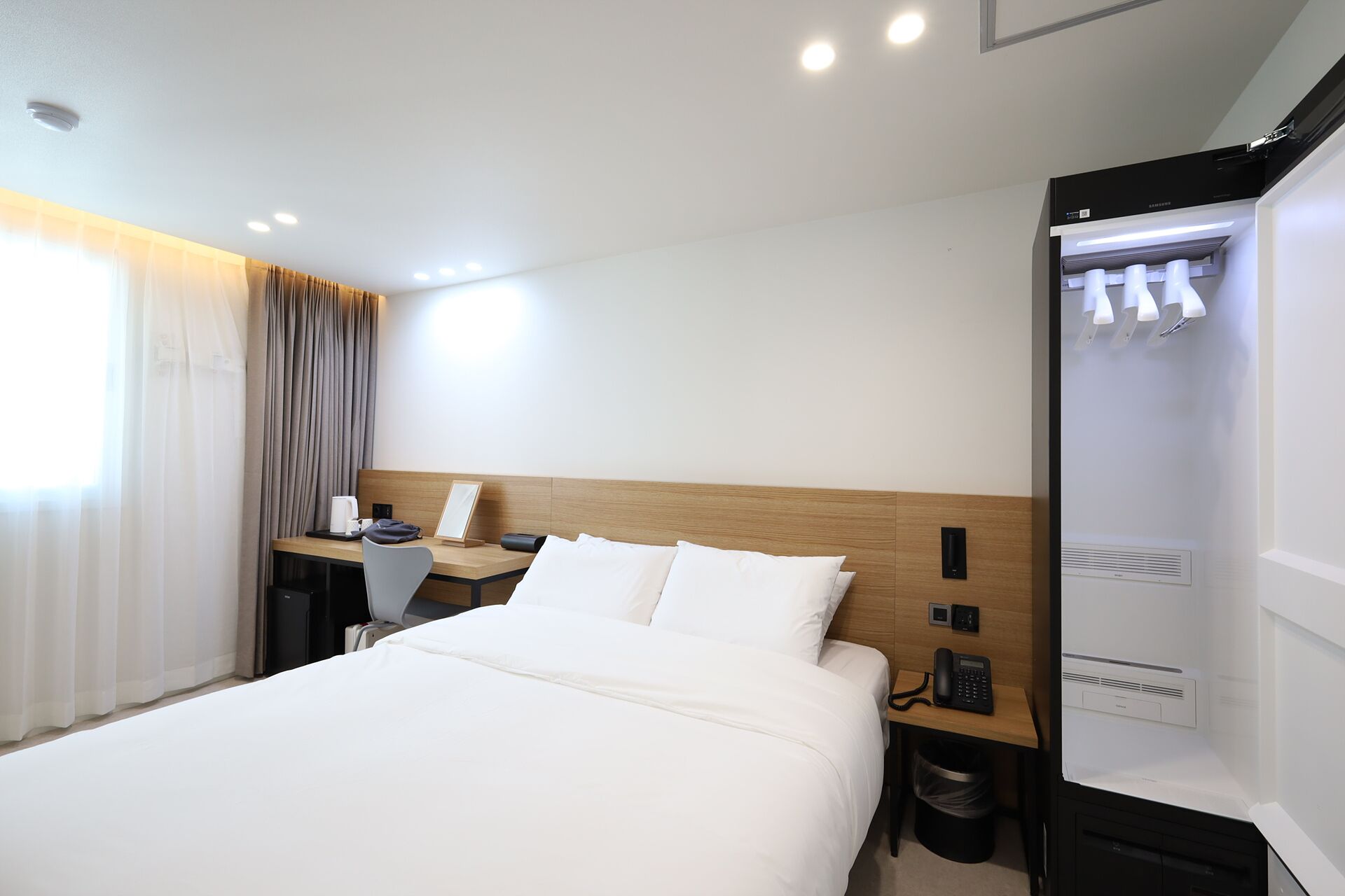 Una habitación de hotel con cama, escritorio, teléfono y minibar.