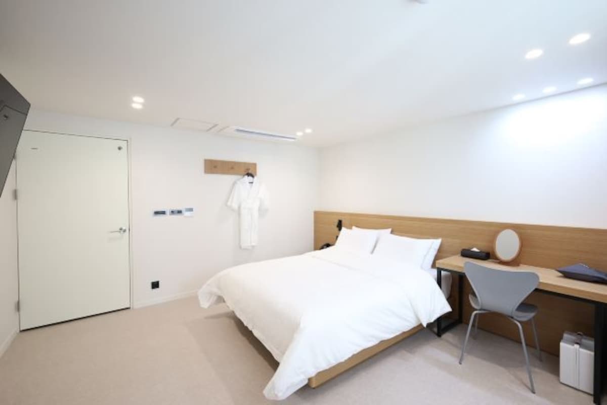 A modern hotel room with a bed, a desk, and a chair.