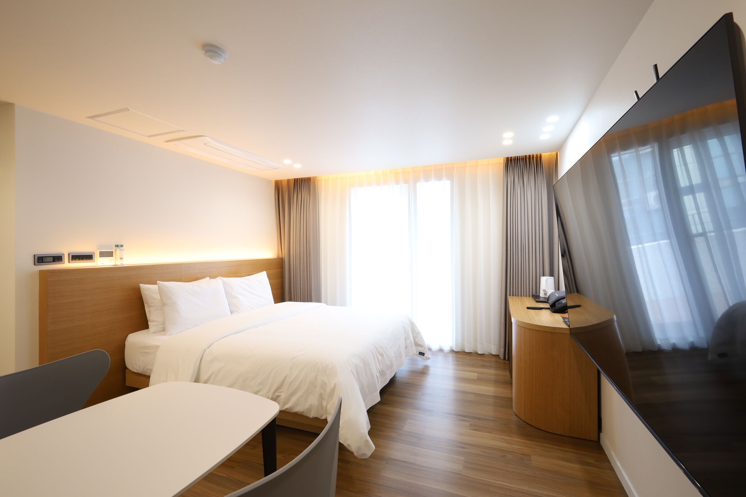 Une chambre d’hôtel moderne, dotée d’un grand lit, d’un bureau et d’une télévision à écran plat.