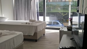 Ein Hotelzimmer mit zwei Betten, einem Fernseher und Blick nach draußen.