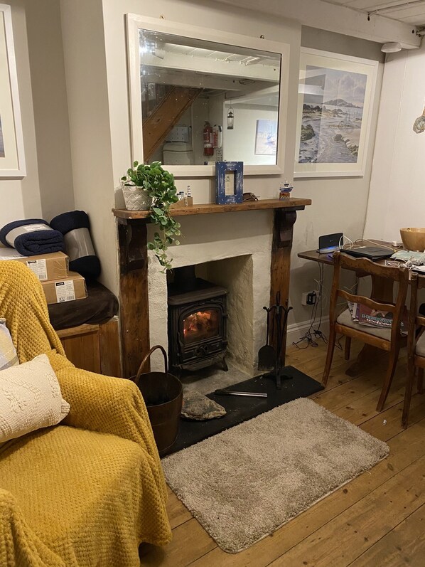 A cozy living room with a fireplace, wooden furniture, and a dining area. - Jacobs Cottage (Port Isaac)