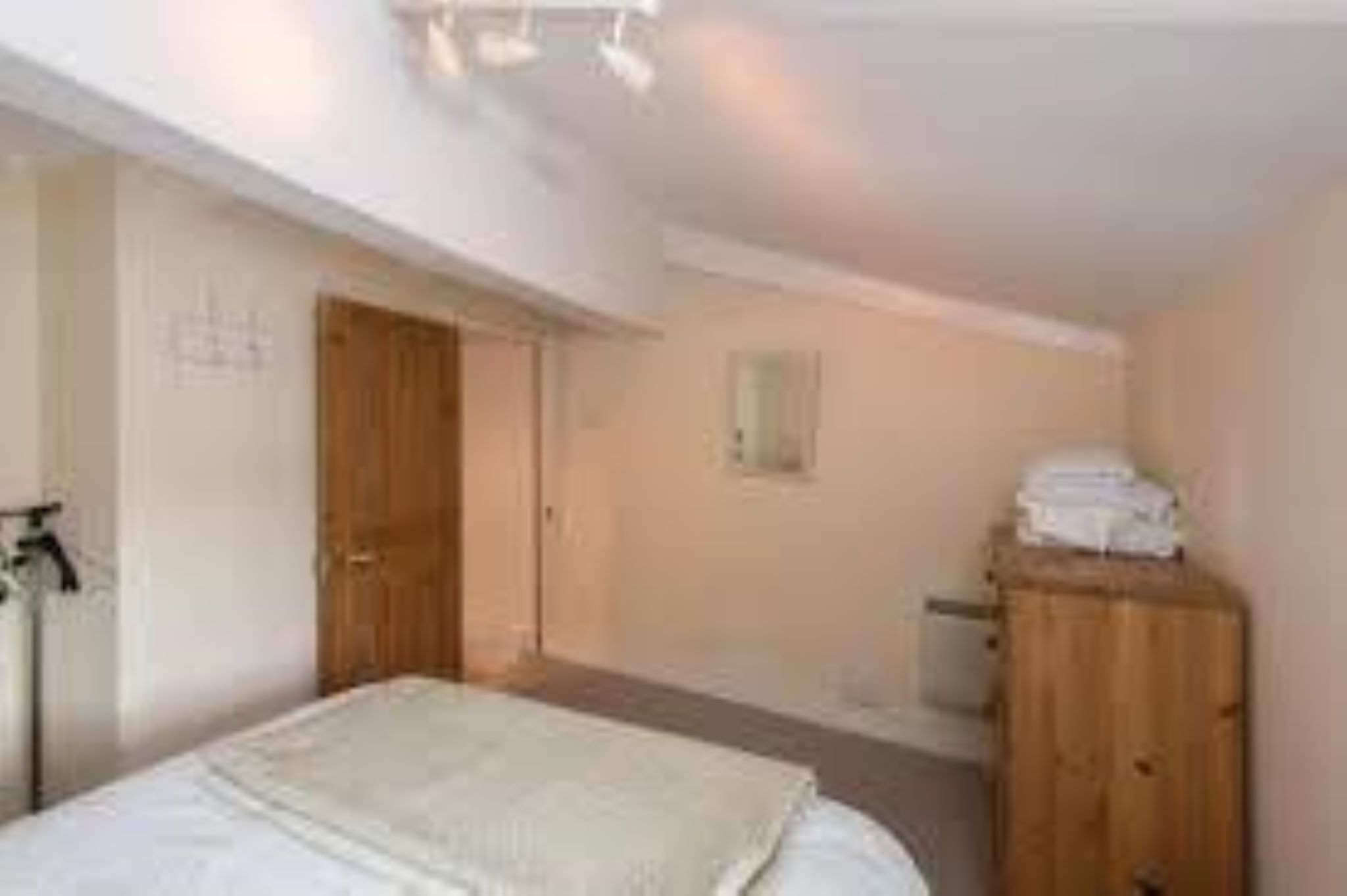 Ein Schlafzimmer mit einem Bett, einem Holzschrank und einer Tür.