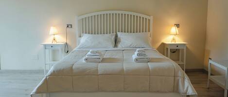 A neatly made bed with a white headboard and footboard, flanked by two bedside tables with lamps.