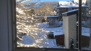 A view through a window of a residential area with snow-covered houses and trees. - Ferienwohnung Hannah Hahnenklee (Goslar)
