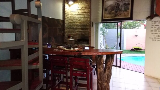 Una cocina rústica con pared de ladrillo, taburetes de madera y una gran mesa de madera.