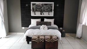 Un dormitorio moderno con una cama grande, decoración temática de cebra y suelo de baldosas.