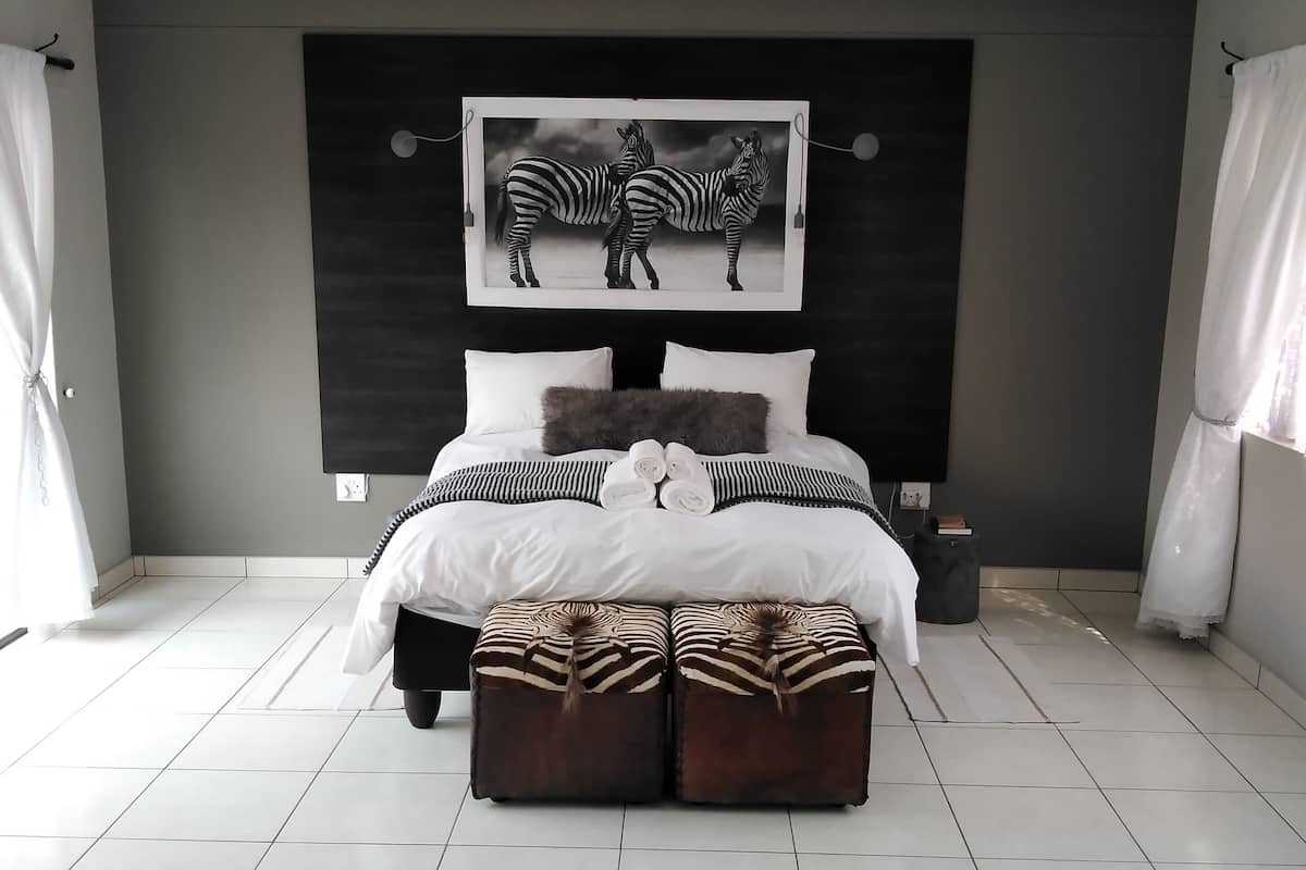 Un dormitorio moderno con una cama grande, decoración temática de cebra y suelo de baldosas.