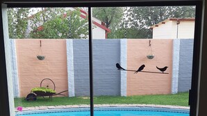 Vista de una piscina con cubierta de madera, un carretillo y cestas colgantes en la pared.