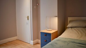 A bedroom with a bed, a nightstand, a drawer, a bedside table, and a door. - Charming 2 Bedroom Cottage in Central Location (Dublin)