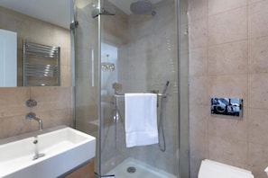 A modern bathroom with a glass-enclosed shower, a white sink, and a towel rack.