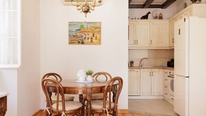 Un comedor con una mesa y sillas de madera, una araña y un cuadro en la pared.