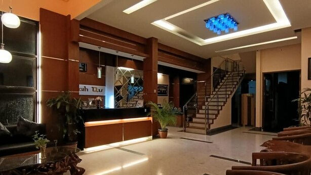 A spacious lobby with a reception desk, a staircase, and a modern ceiling design. - Omahqu Guest House (Yogyakarta)