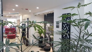 A modern interior with a living area featuring red sofas, black chairs, and potted plants. - Palermo Bridge (Buenos Aires)