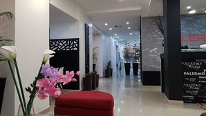A modern hotel lobby with a red seating area, black decorative panels, and potted plants. - Palermo Bridge (Buenos Aires)