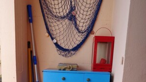Una habitación con un armario azul, un farolillo rojo, una hamaca y una alfombra colorida que representa un paisaje.
