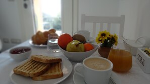 A breakfast table with toast, fruit, a cup of coffee, and a glass of orange juice. - La Casa dei Limoni (Genoa)