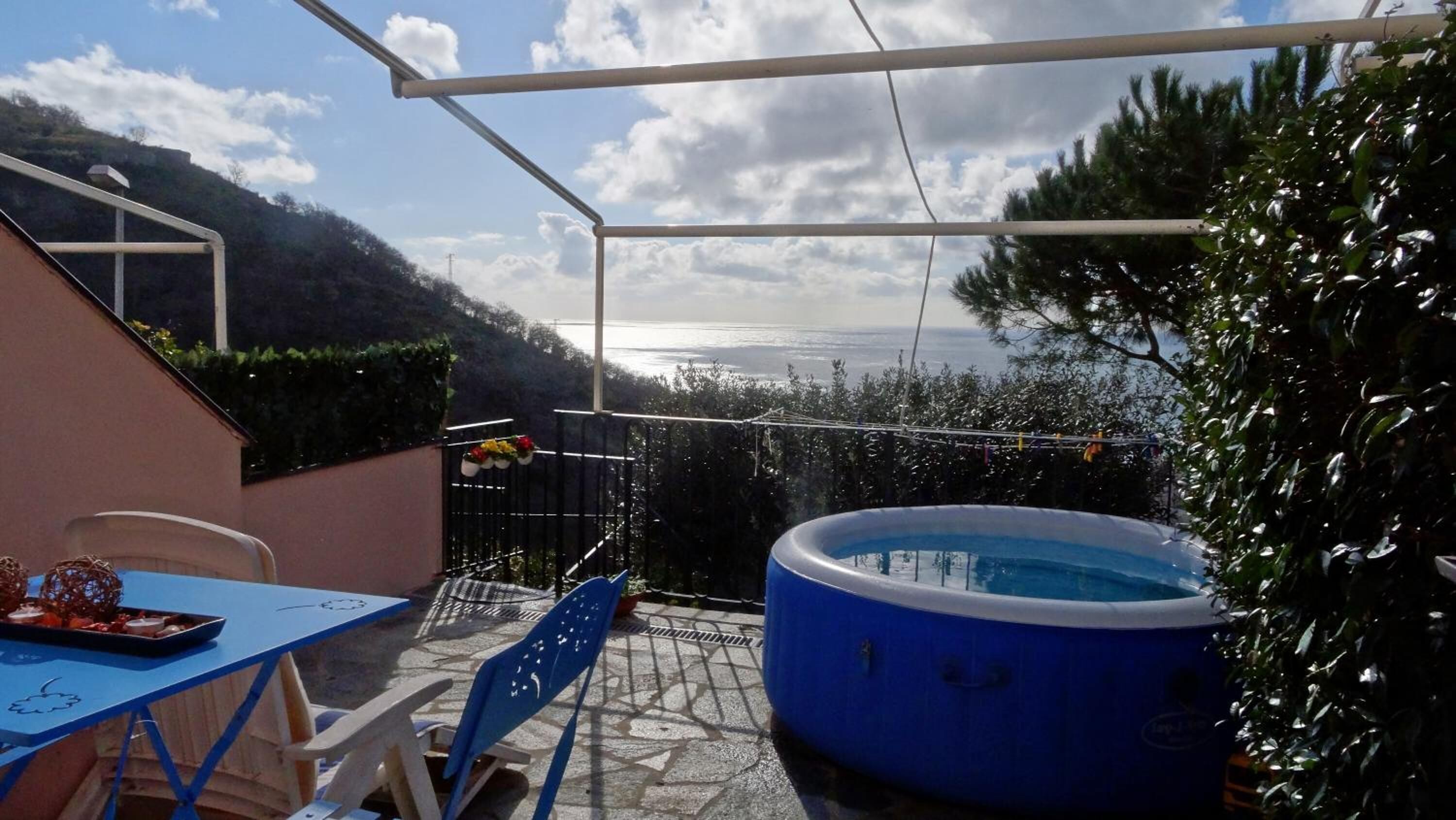 Un patio con una piscina gonfiabile blu, un tavolo con sedie e vista sul mare.