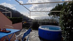 A patio with a blue inflatable pool, a table with chairs, and a view of the sea. - La Casa dei Limoni (Genoa)
