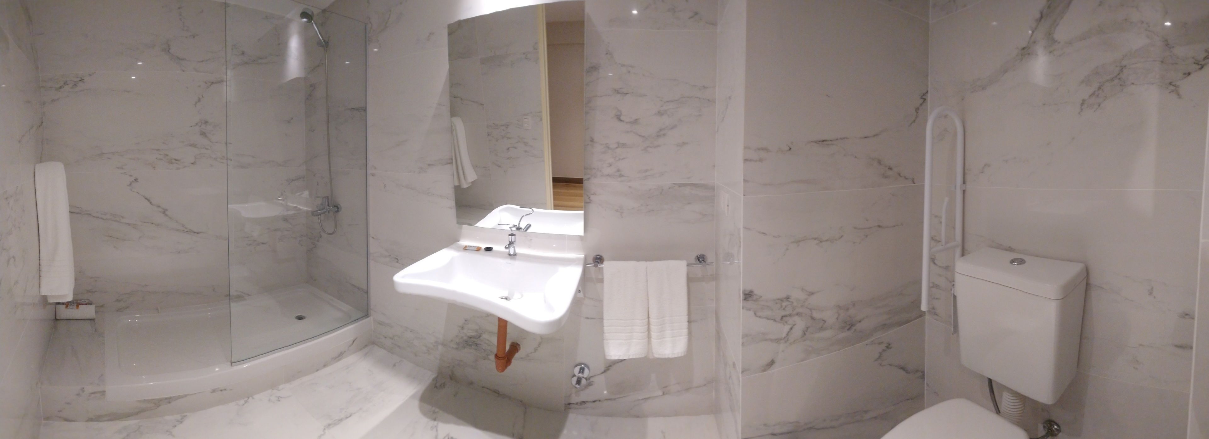 A modern bathroom with a glass-enclosed shower, a built-in sink, and a toilet.