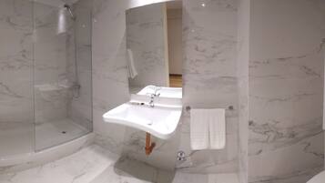 A modern bathroom with a glass-enclosed shower, a built-in sink, and a toilet.