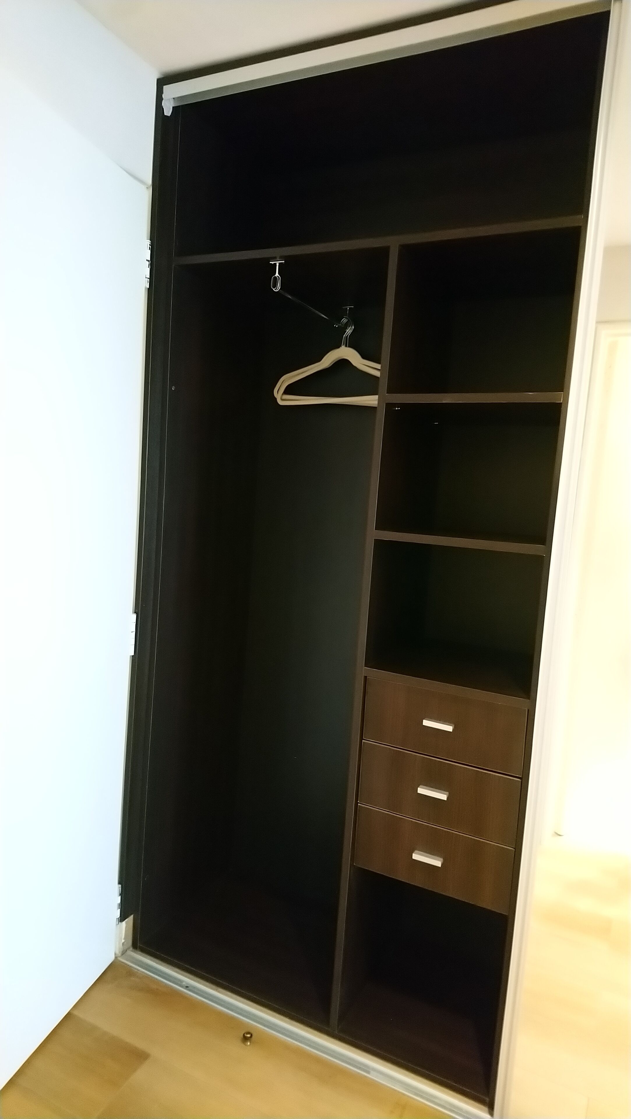 Un vestidor con barra para colgar y varios cajones.