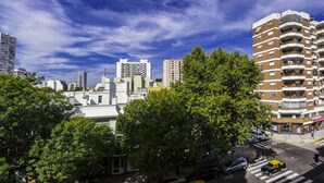 A cityscape with high-rise buildings, a crosswalk, and a yellow taxi. - Avellaneda Aparts & Suites (Buenos Aires)