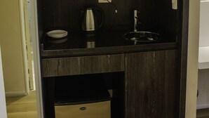 A compact kitchenette with a coffee maker, sink, and storage shelves. - Avellaneda Aparts & Suites (Buenos Aires)
