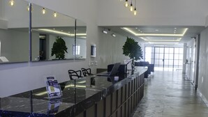 A modern reception area with a marble counter, a large mirror, and hanging light fixtures. - Avellaneda Aparts & Suites (Buenos Aires)