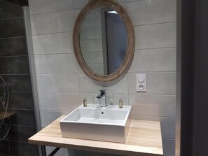 A bathroom with a white sink, a mirror, and a light switch on the wall.