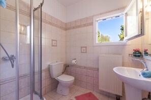 A bathroom with a shower, toilet, sink, and a window. - Marina Gouvia Family Villa By Konnect (Corfu)