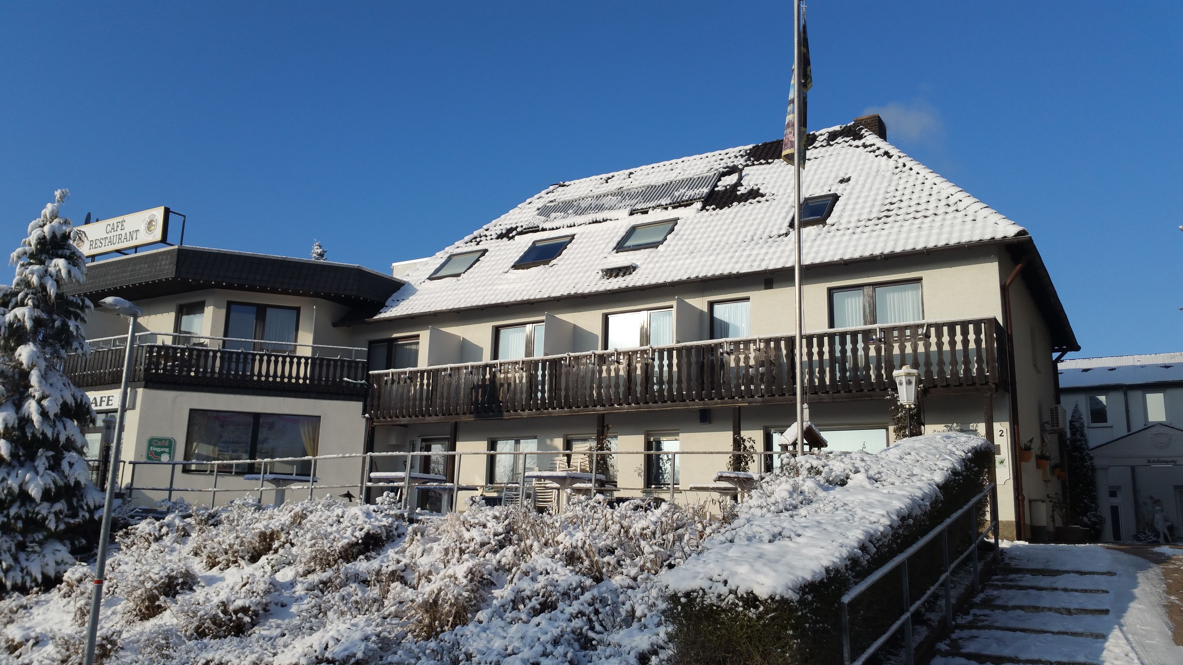 Een hotel met een met sneeuw bedekte dak, balkons en een bordje dat een restaurant aangeeft.
