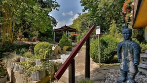 A garden with a statue, a gazebo, and a stone staircase. - Themenhotel Terrassen Café (Bad Muender am Deister)