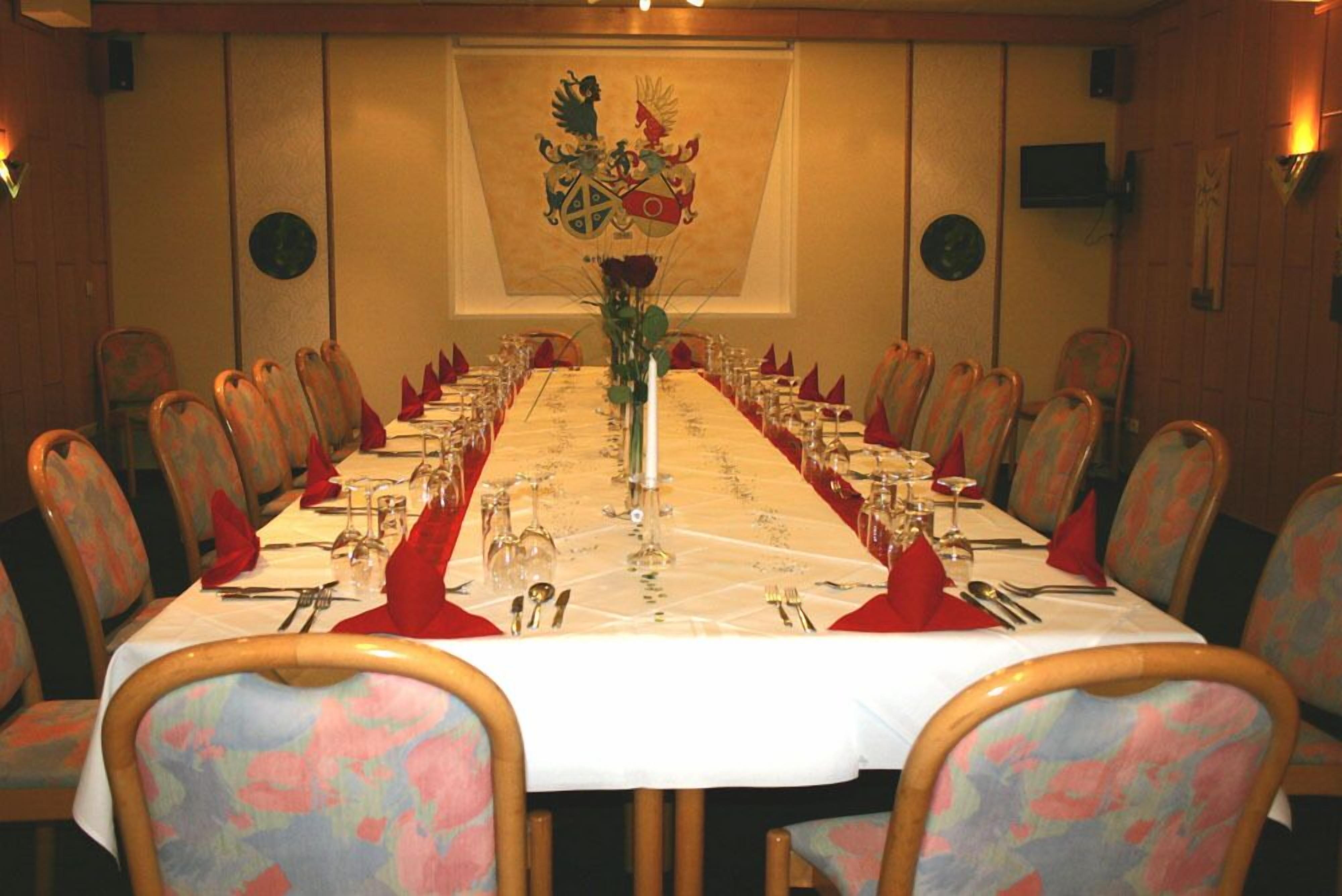 Ett konferensrum med ett långt bord uppdukat för ett möte, omgivet av stolar med blommigt tyg.