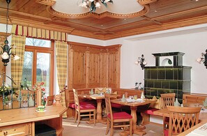 A dining area with wooden furniture, a fireplace, and a view of the outdoors. - Hotel Jägerhaus (Sankt Peter)