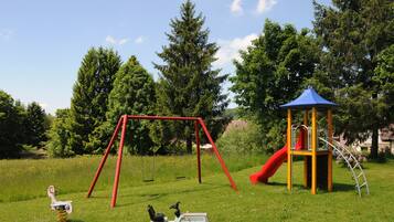 A playground with swings, a slide, and a small tractor toy.