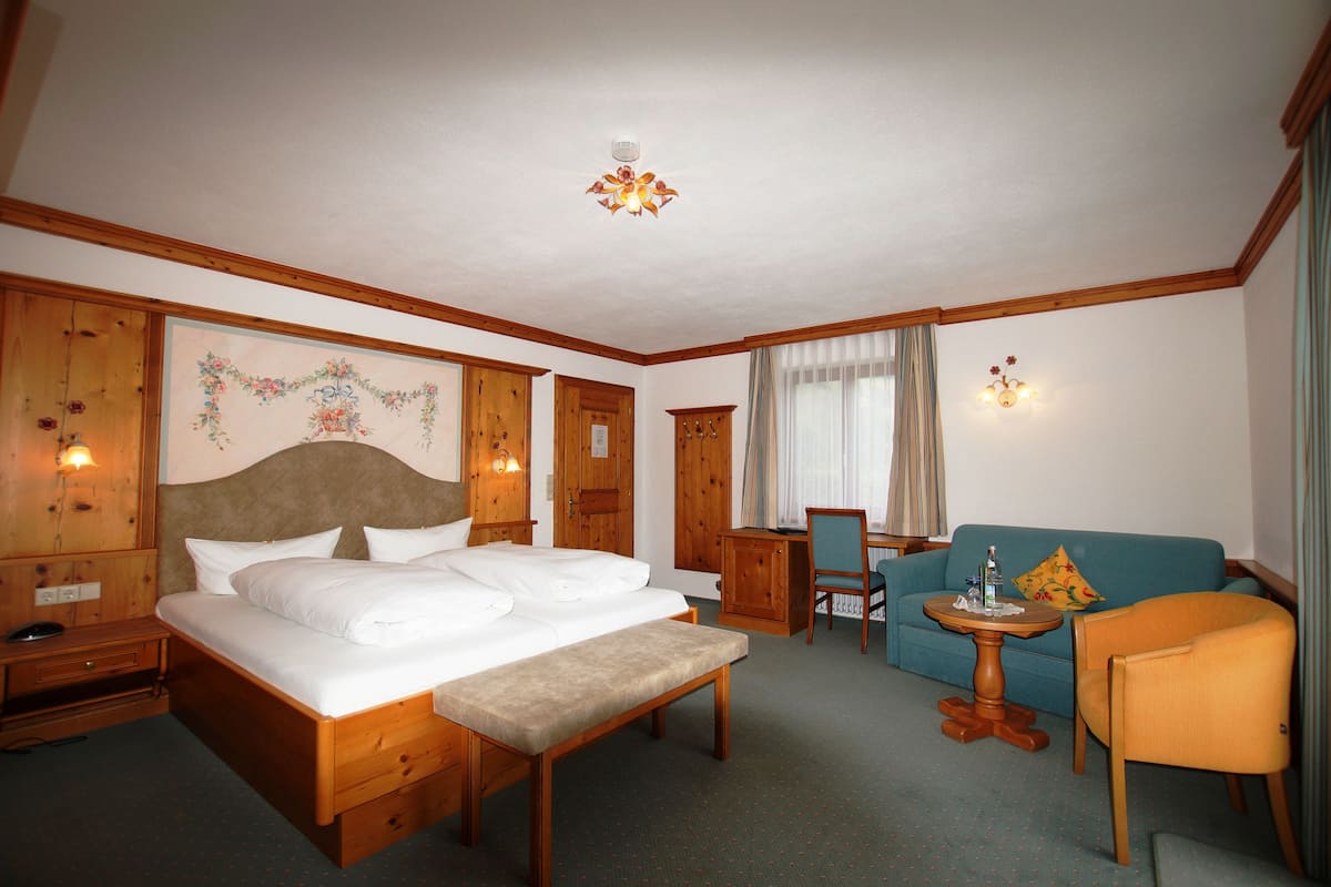 Una habitación de hotel con una cama grande, un escritorio, una silla, un sofá y una mesita.