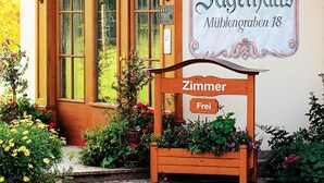 A hotel entrance with a sign reading "HOTEL Jägerhaus Mühlengraben 18" and a wooden bench labeled "Zimmer Frei". - Hotel Jägerhaus (Sankt Peter)
