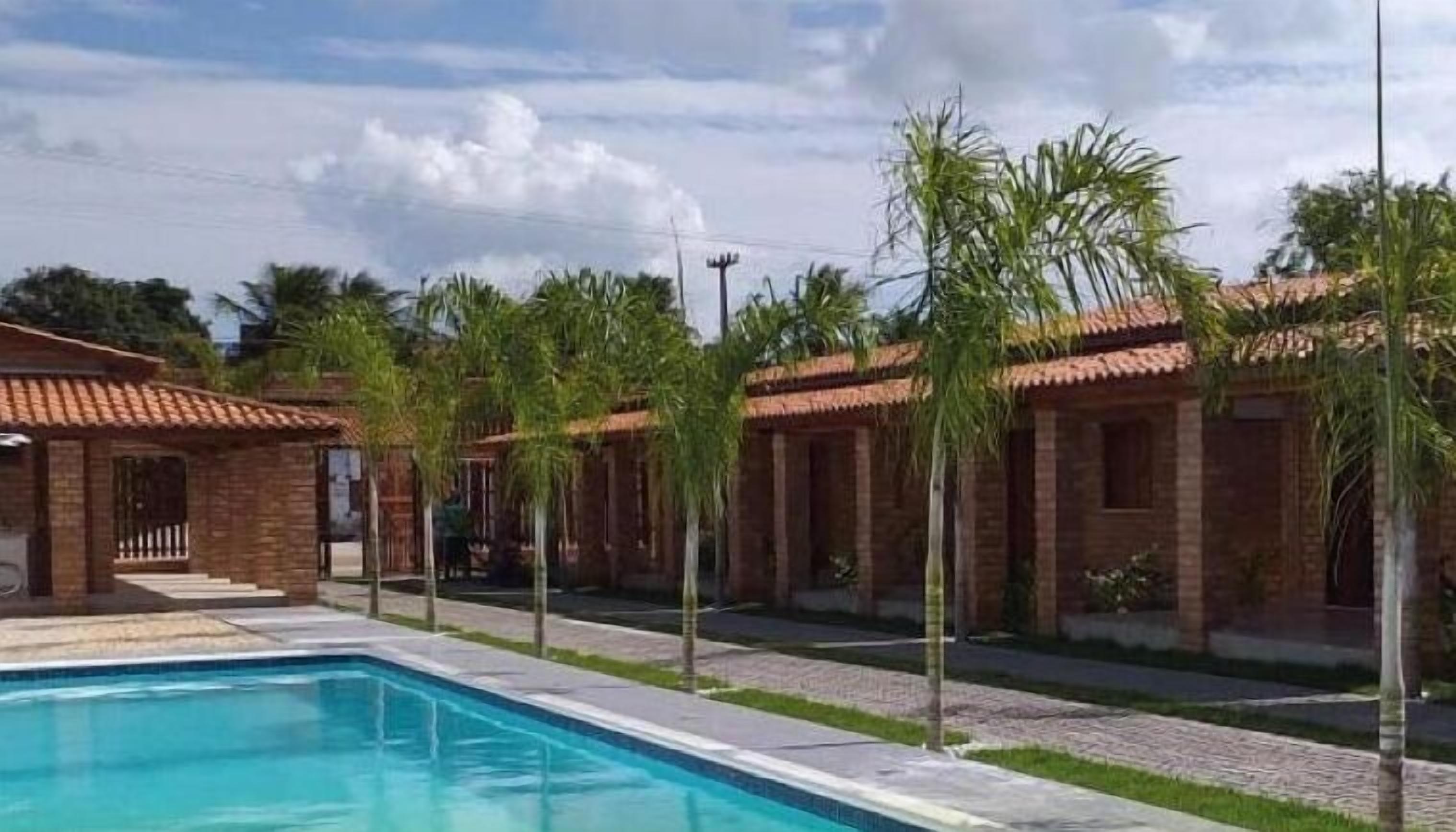 A poolside area with a swimming pool, brick buildings, and palm trees.